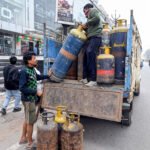 A worker carries a LPG cylinder