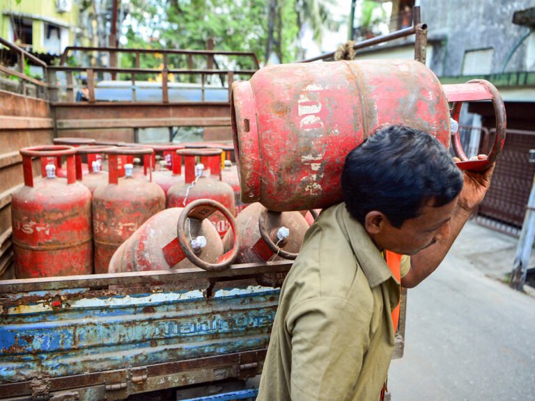 A worker carries an LPG cylinder