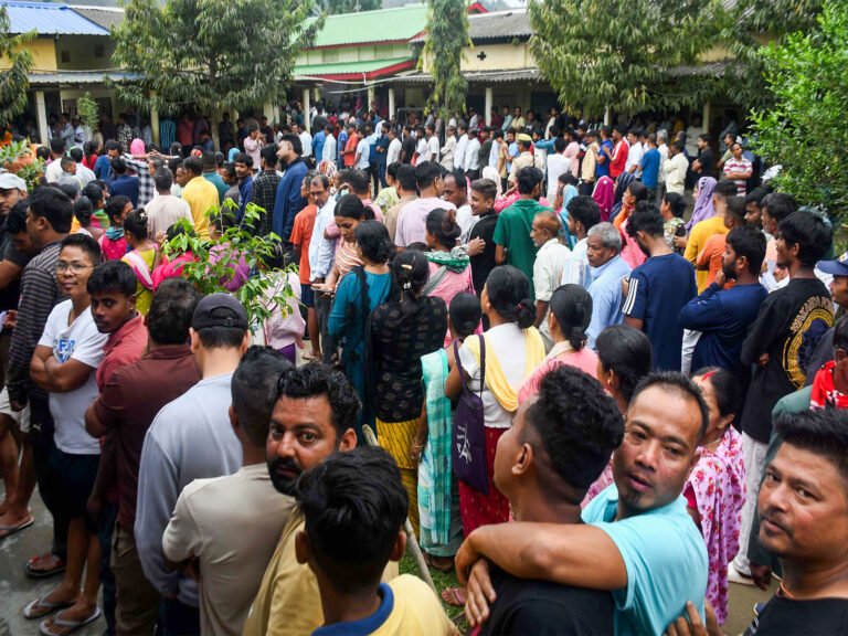 Voters wait in queues to cast their votes at a polling station in Assam